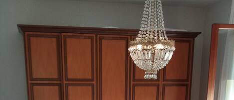 A bedroom with a wooden bed, a large wardrobe, and a chandelier.