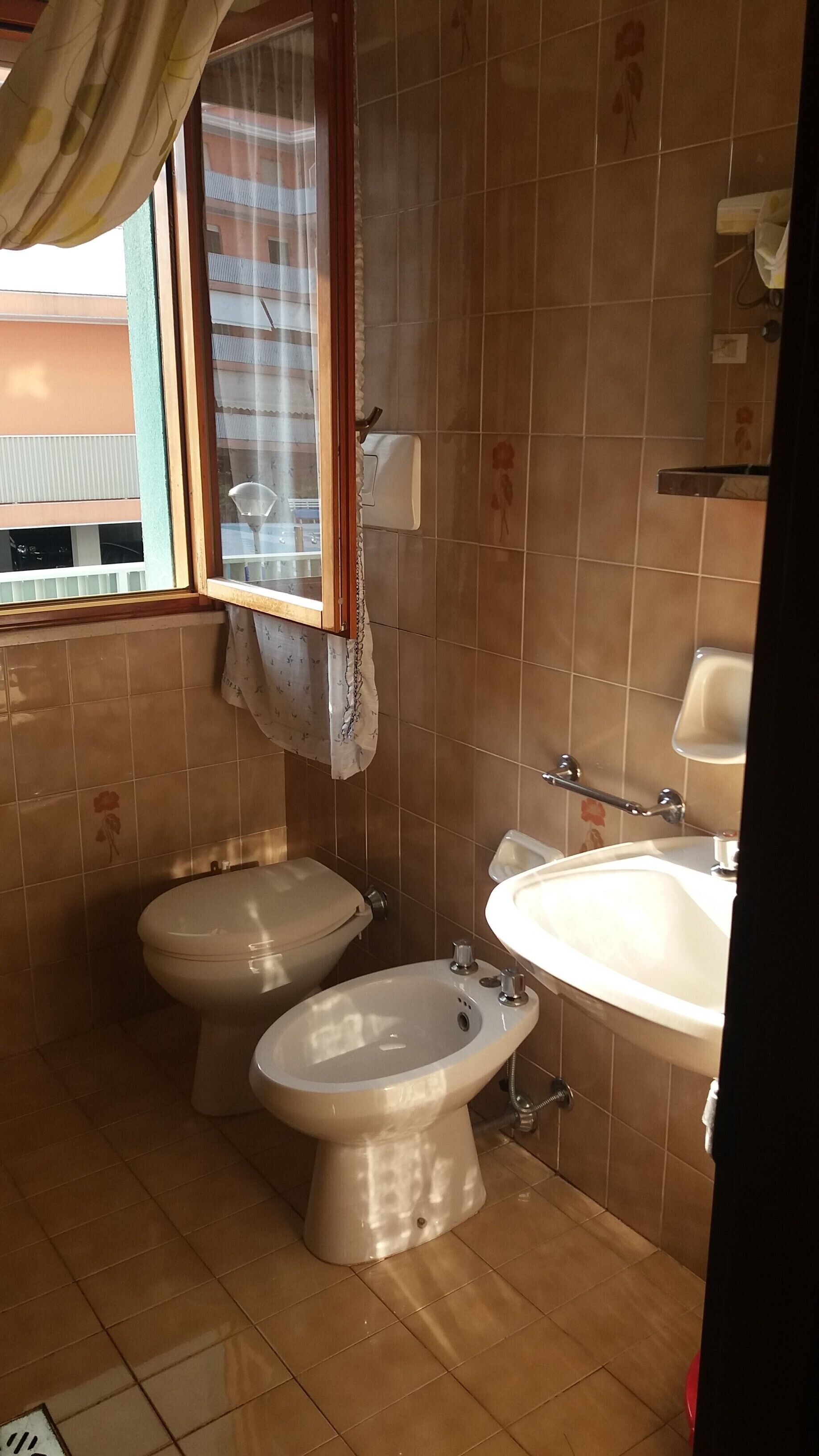 A bathroom with two toilets, a bidet, and a sink.