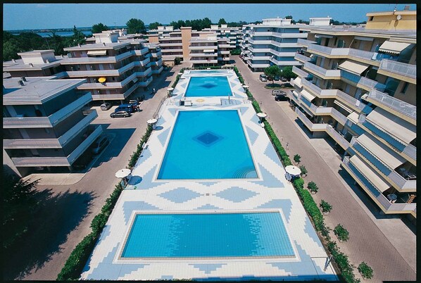 Un hôtel doté de nombreux balcons, d’une piscine centrale et d’un parking.