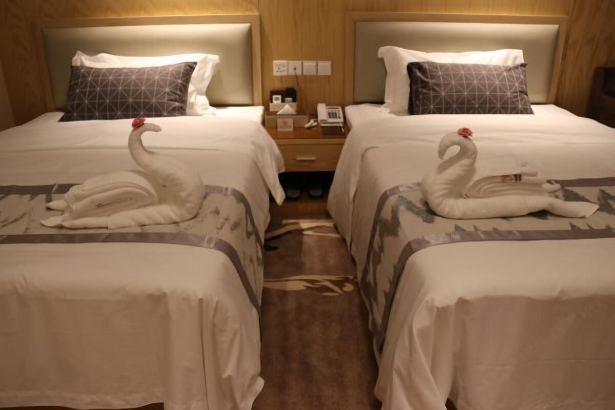 Two beds with white linens and decorative swan towels.