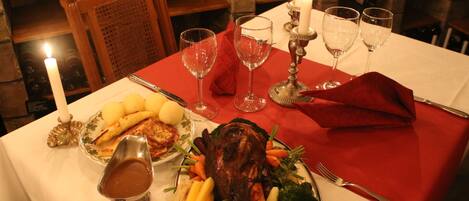A dining table with a red tablecloth, a roasted meat centerpiece, and various side dishes.