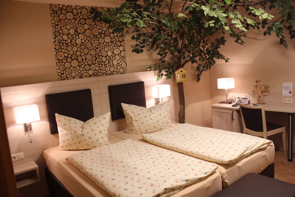 Habitación de hotel con dos camas, un escritorio y una silla.