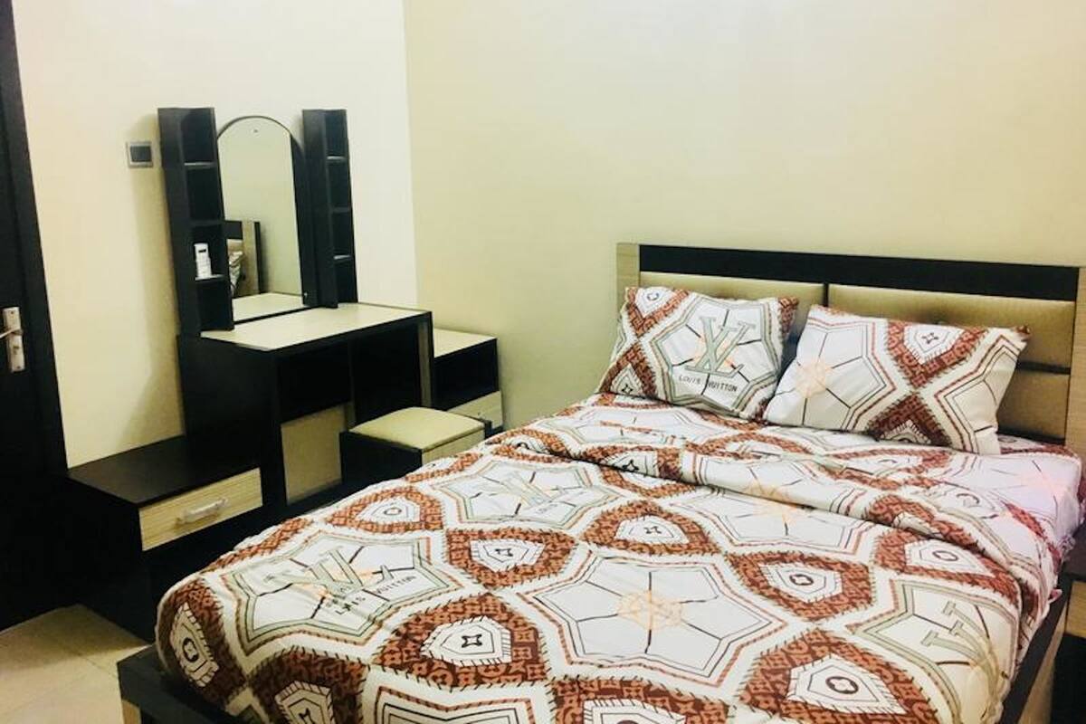 A bedroom with a bed, a dresser, and a mirror.
