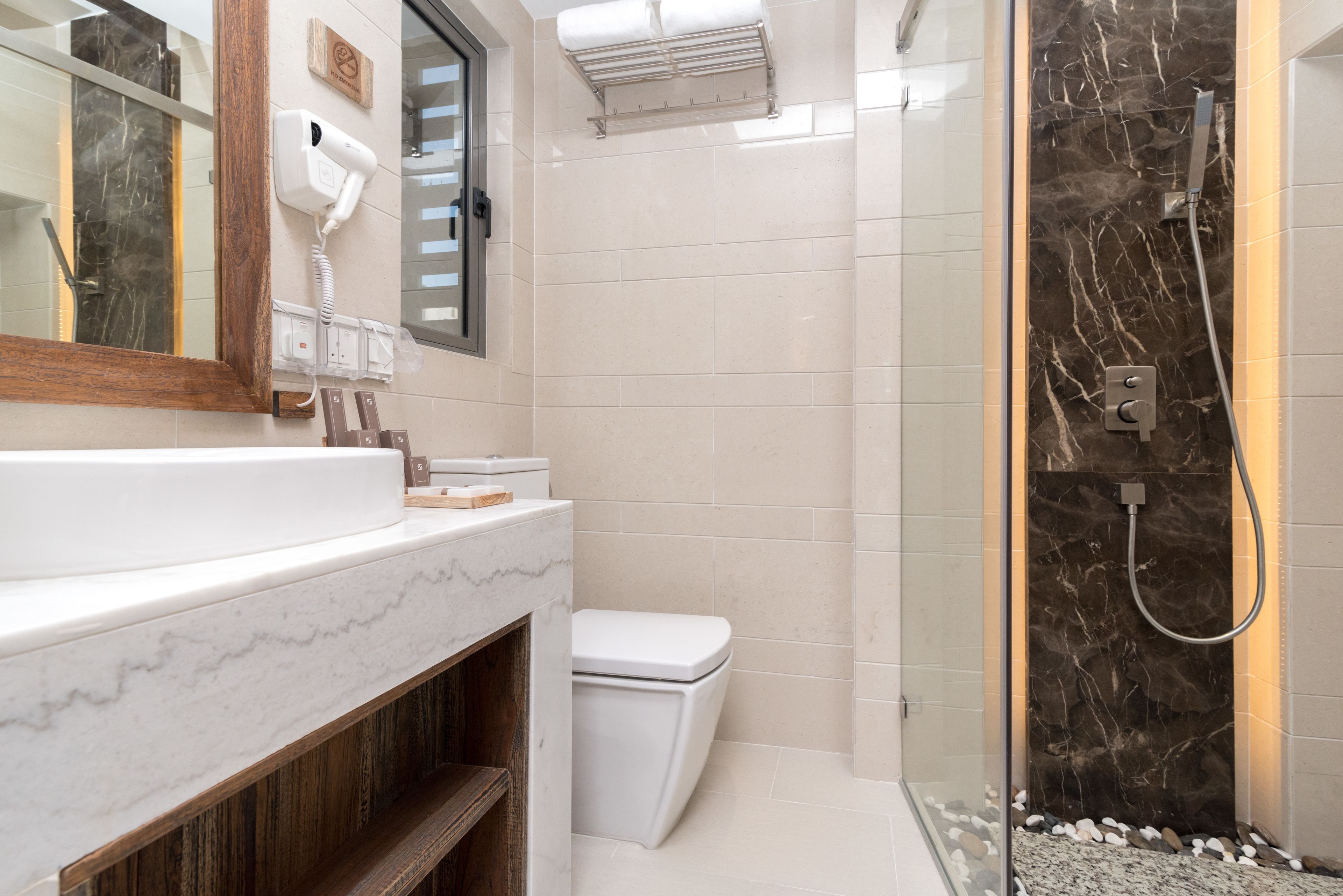 Een moderne badkamer met een marmeren wastafel, toilet en een douchecabine met glazen wanden.