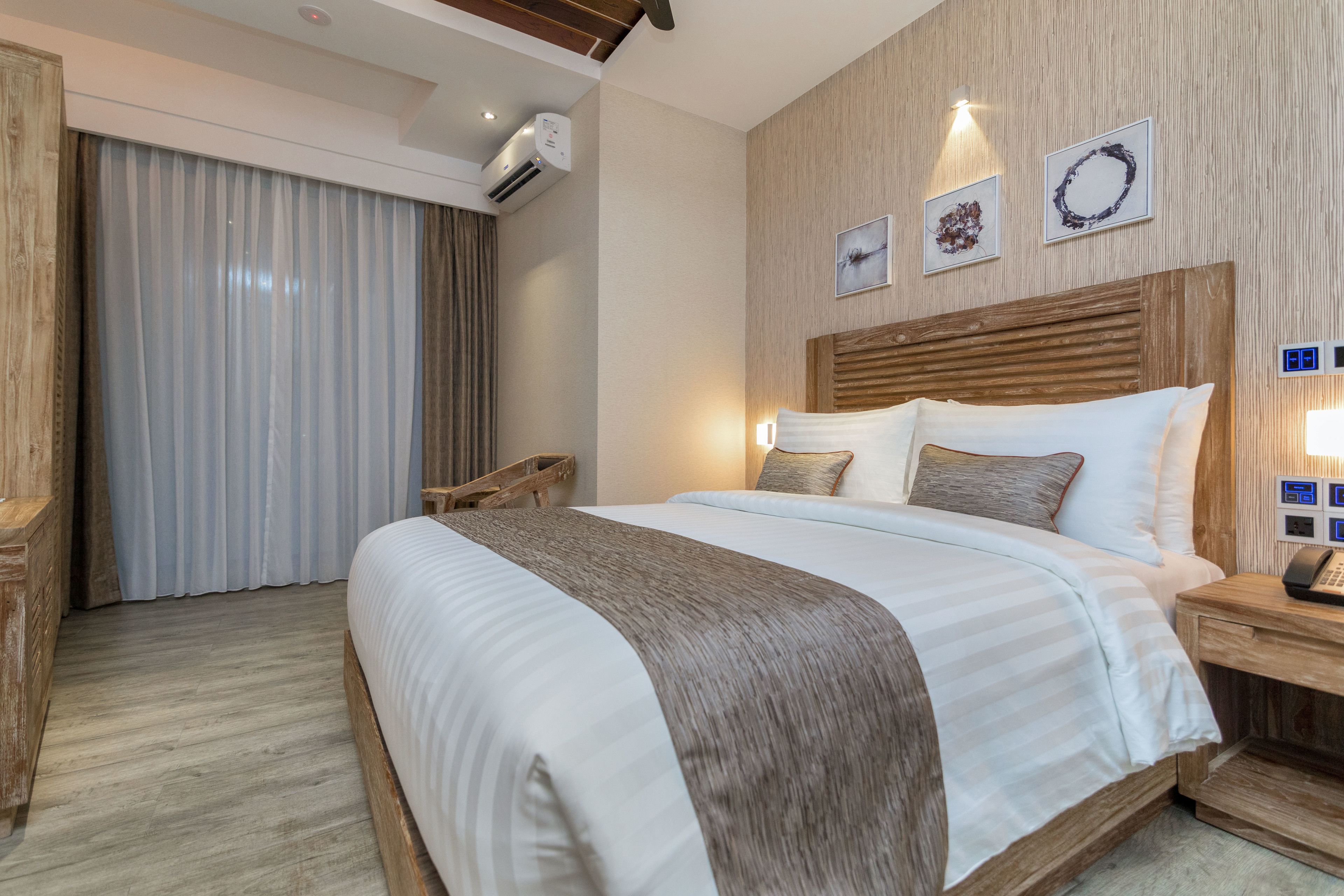A hotel room with a large bed, wooden headboard, and a nightstand with a phone.