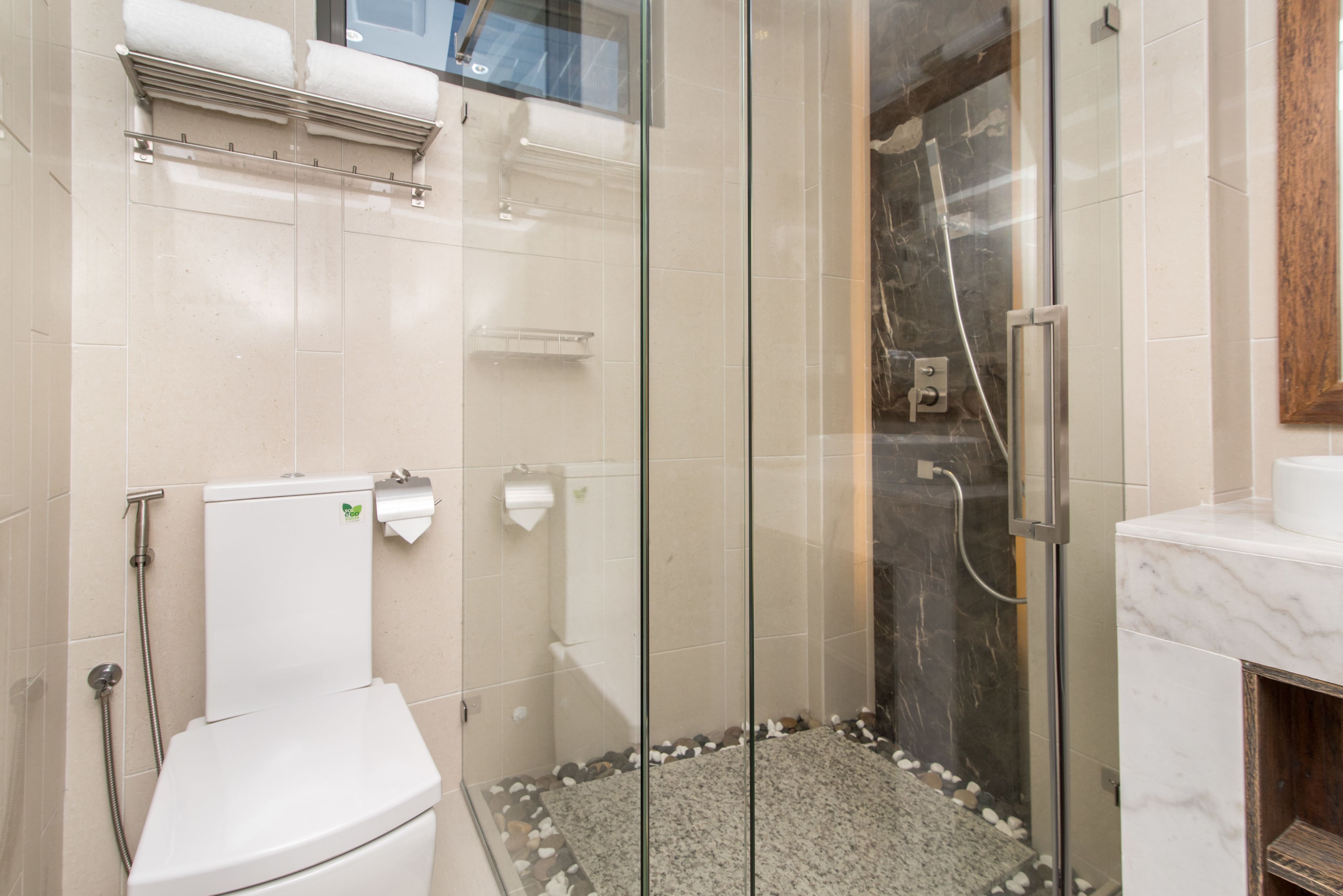 A modern bathroom with a glass-enclosed shower, a toilet, and a marble countertop.