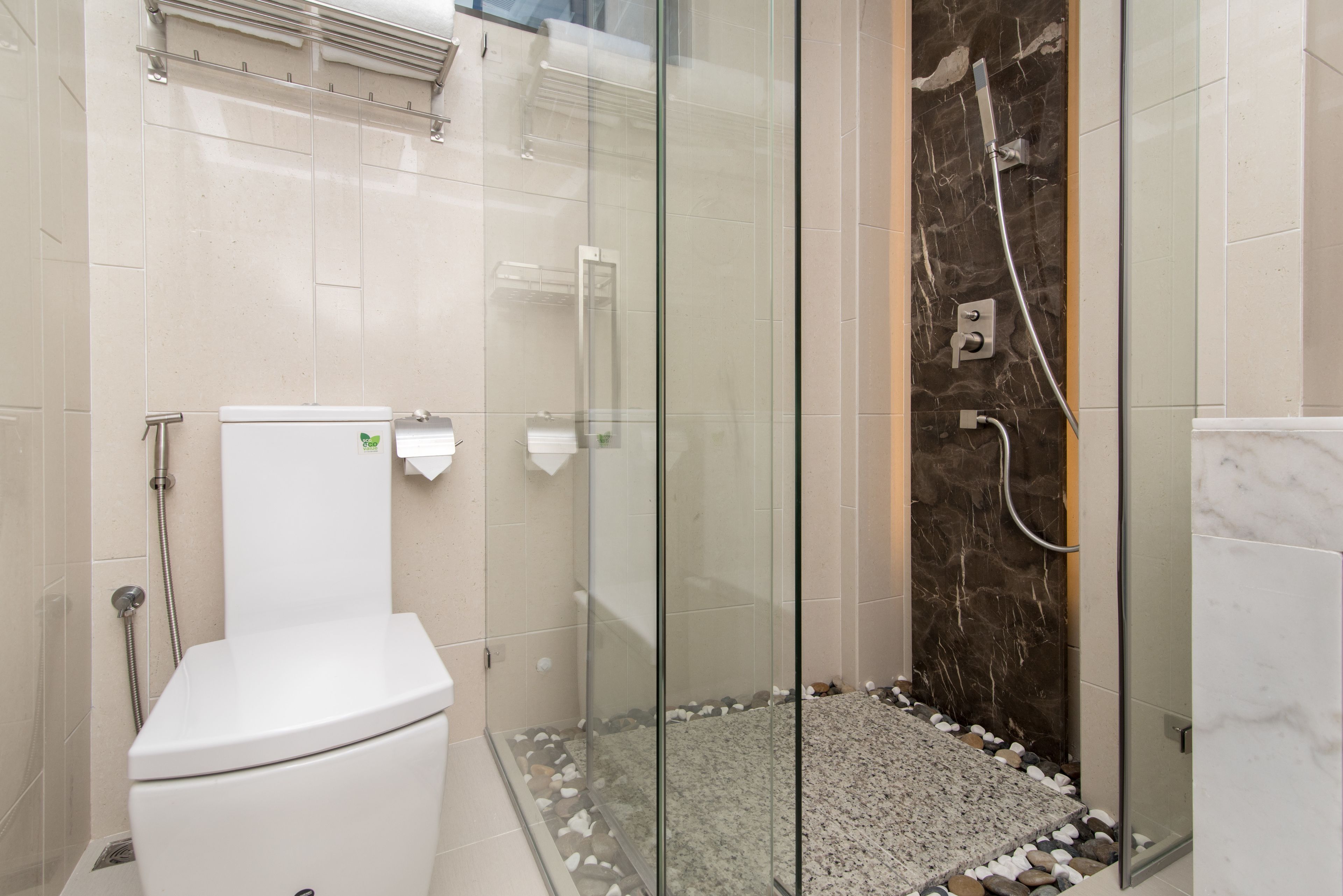 A modern bathroom with a glass-enclosed shower, a white toilet, and a marble-tiled shower wall.