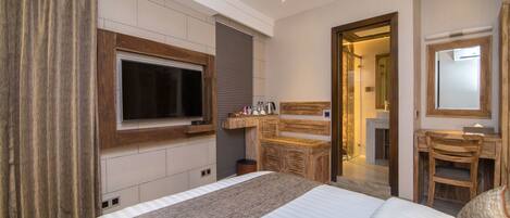 A modern hotel room with a large bed, a television mounted on the wall, a wooden desk, and a mirror.
