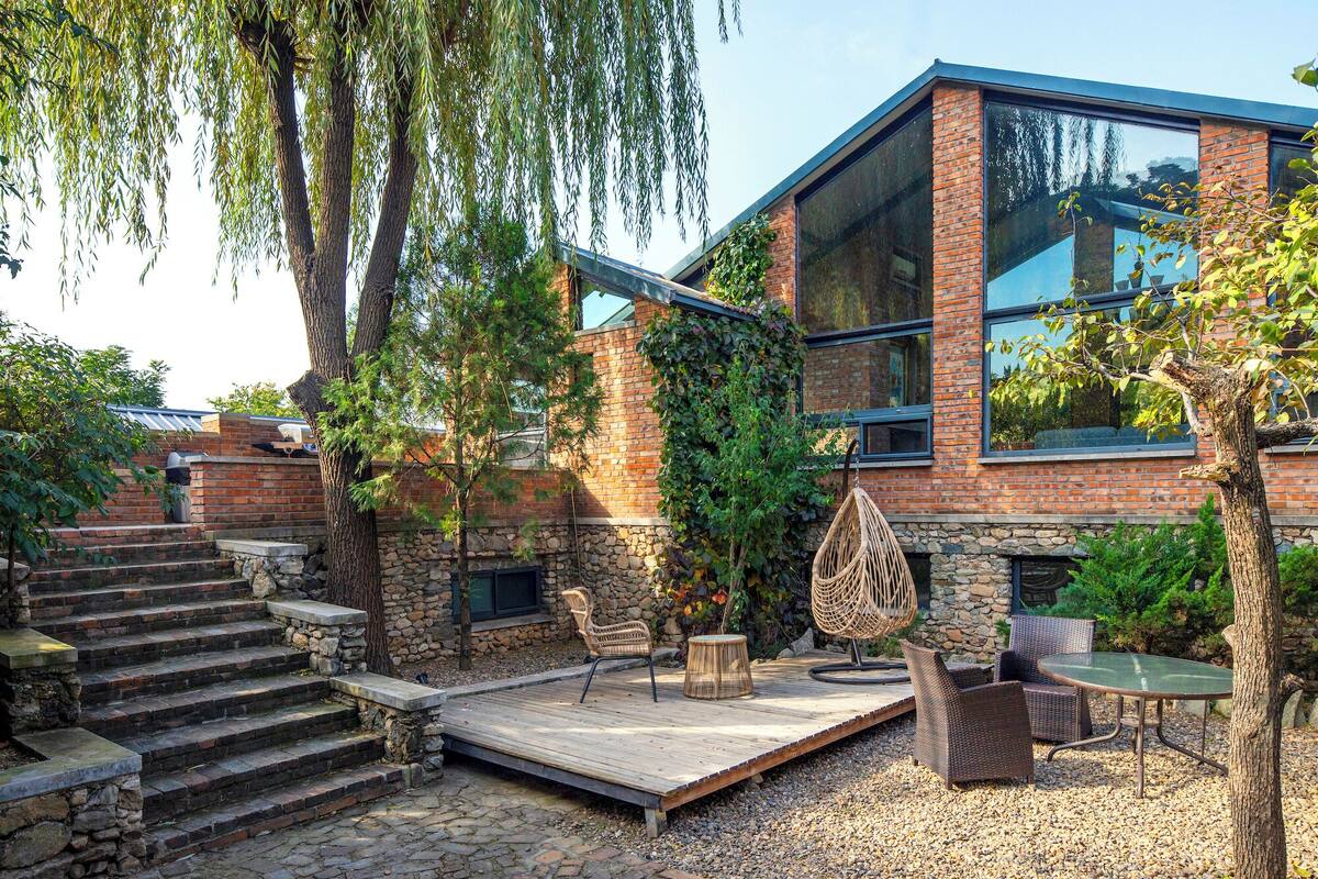 A modern building with a stone staircase, outdoor seating area, and a wooden deck.