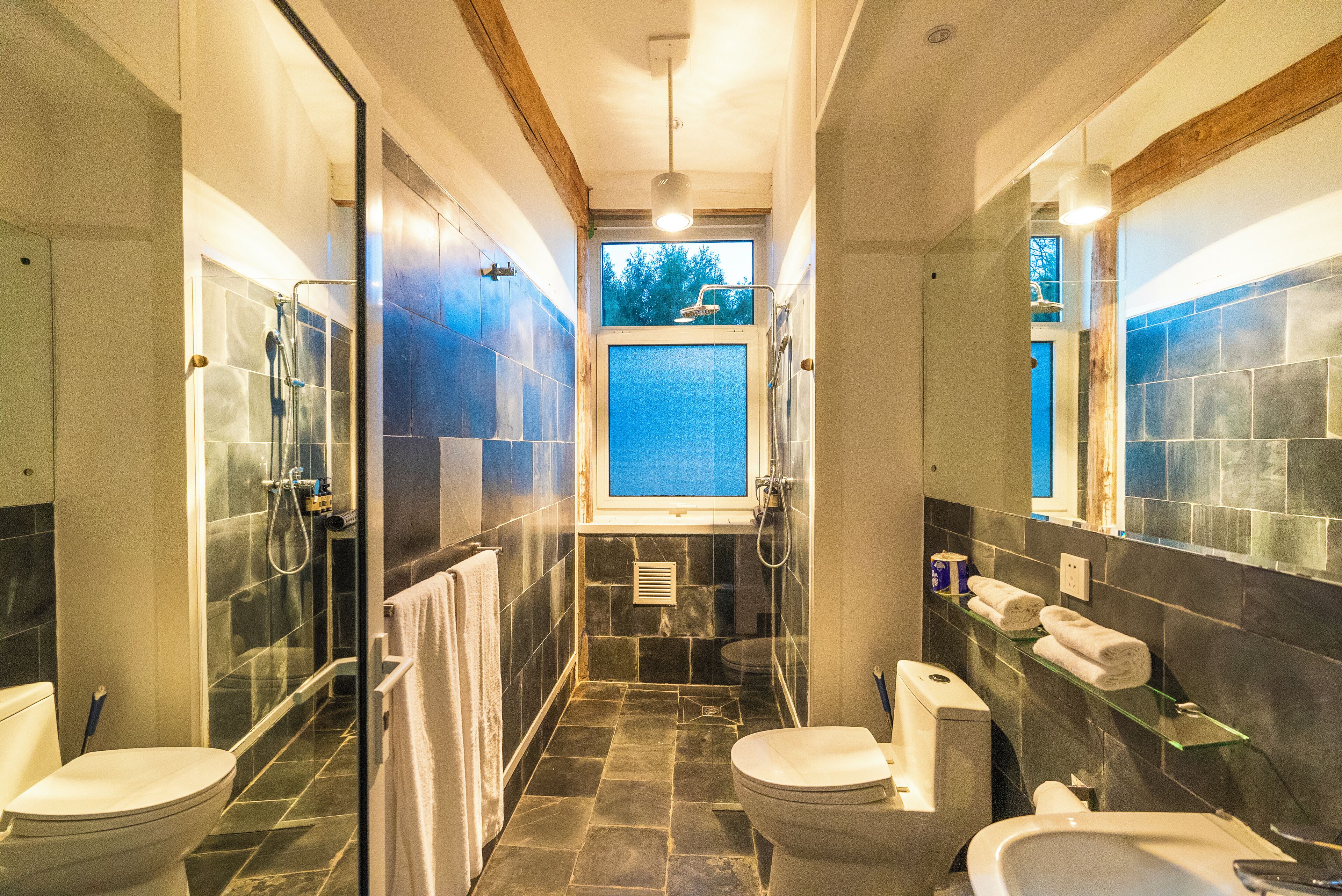 A bathroom with two toilets, a shower, and a sink.