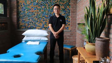 Relax in a serene space with a massage table, pillow, and comfortable seating area.