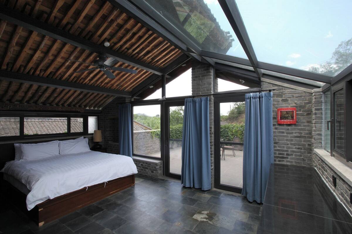 A bedroom with a large bed, a skylight, and a view of the outdoors.