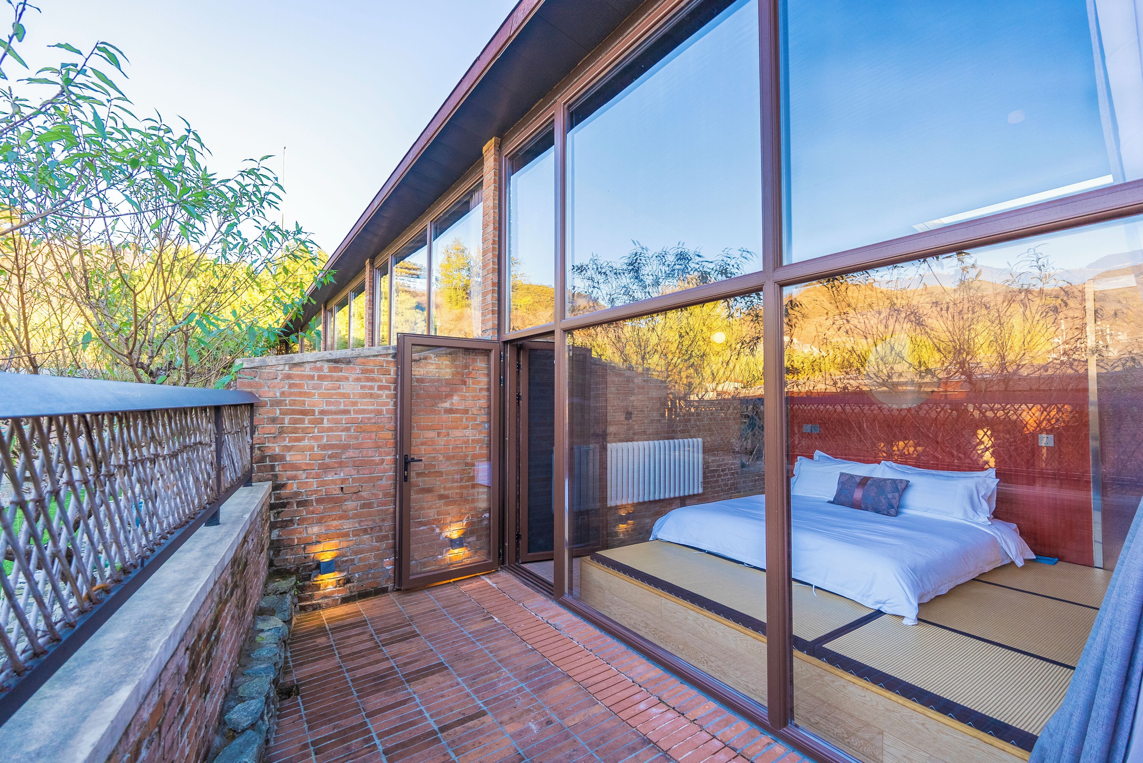 A room with large windows, a bed, and a view of trees.