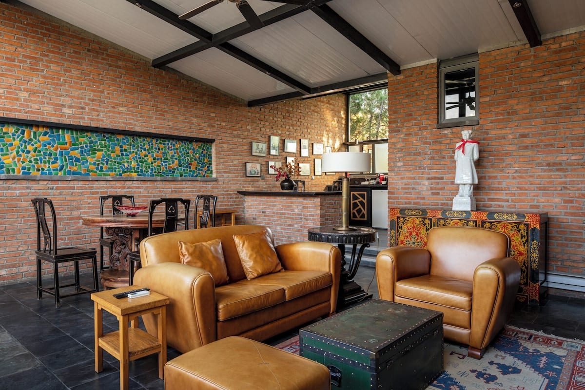 A cozy living room with leather furniture, a mosaic wall, and a brick interior.