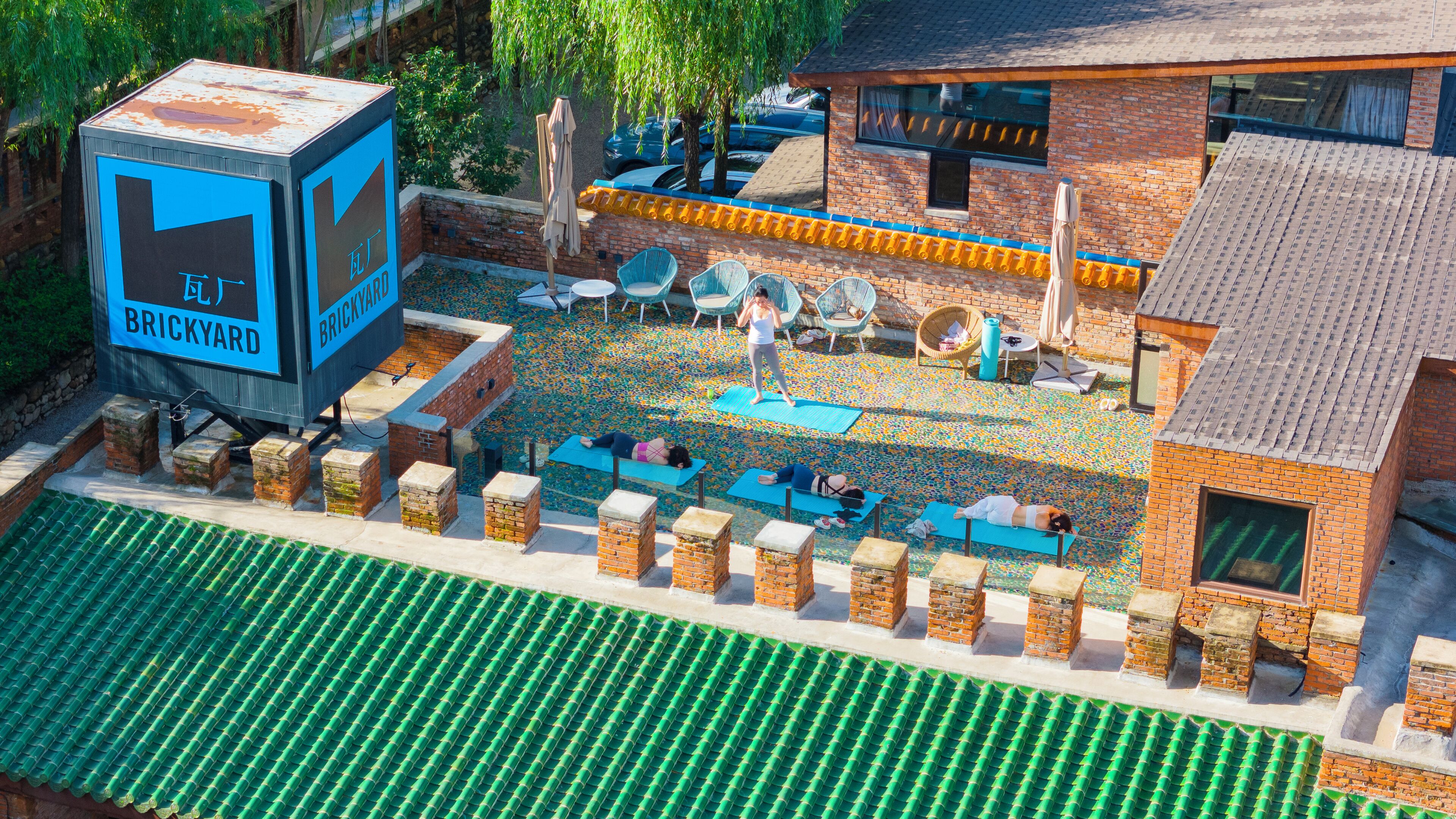 A rooftop patio with exercise mats, outdoor furniture, and a sign for 'Brick Yard'.