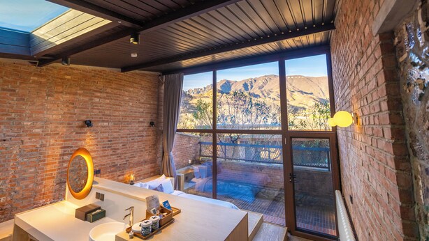 Ein modernes Badezimmer mit großem Fenster, Oberlicht und Bergblick.
