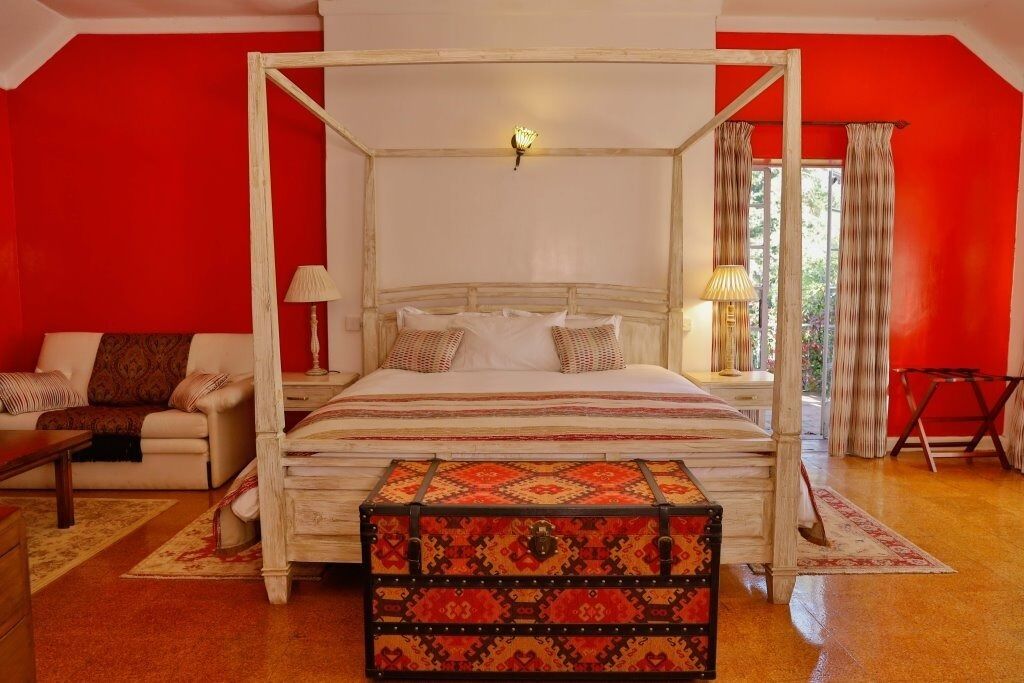 A four-poster bed with a canopy, a wooden chest of drawers, a sofa with cushions, and a small table.
