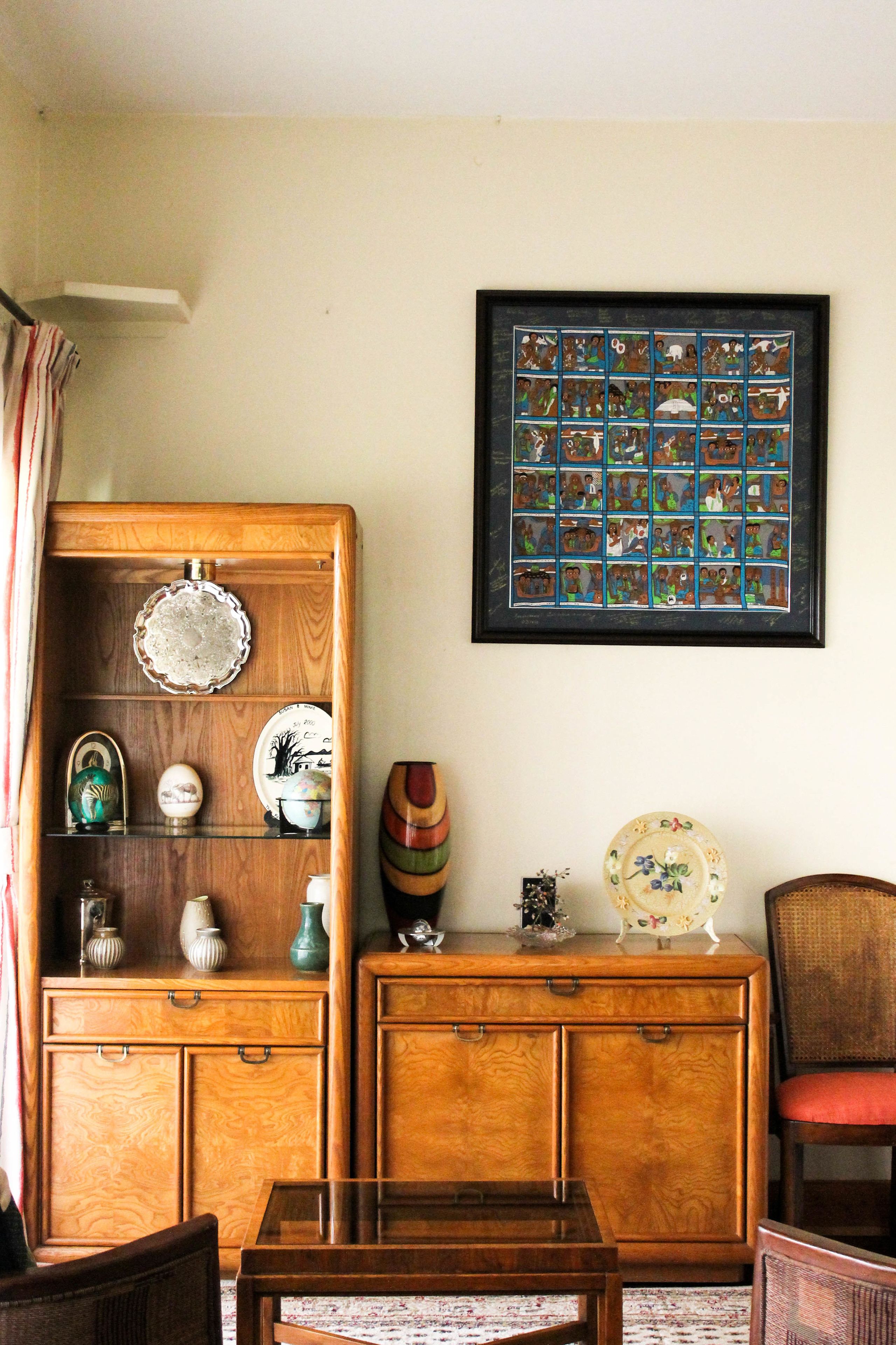 Una habitación con un armario de madera, un collage enmarcado y una silla.