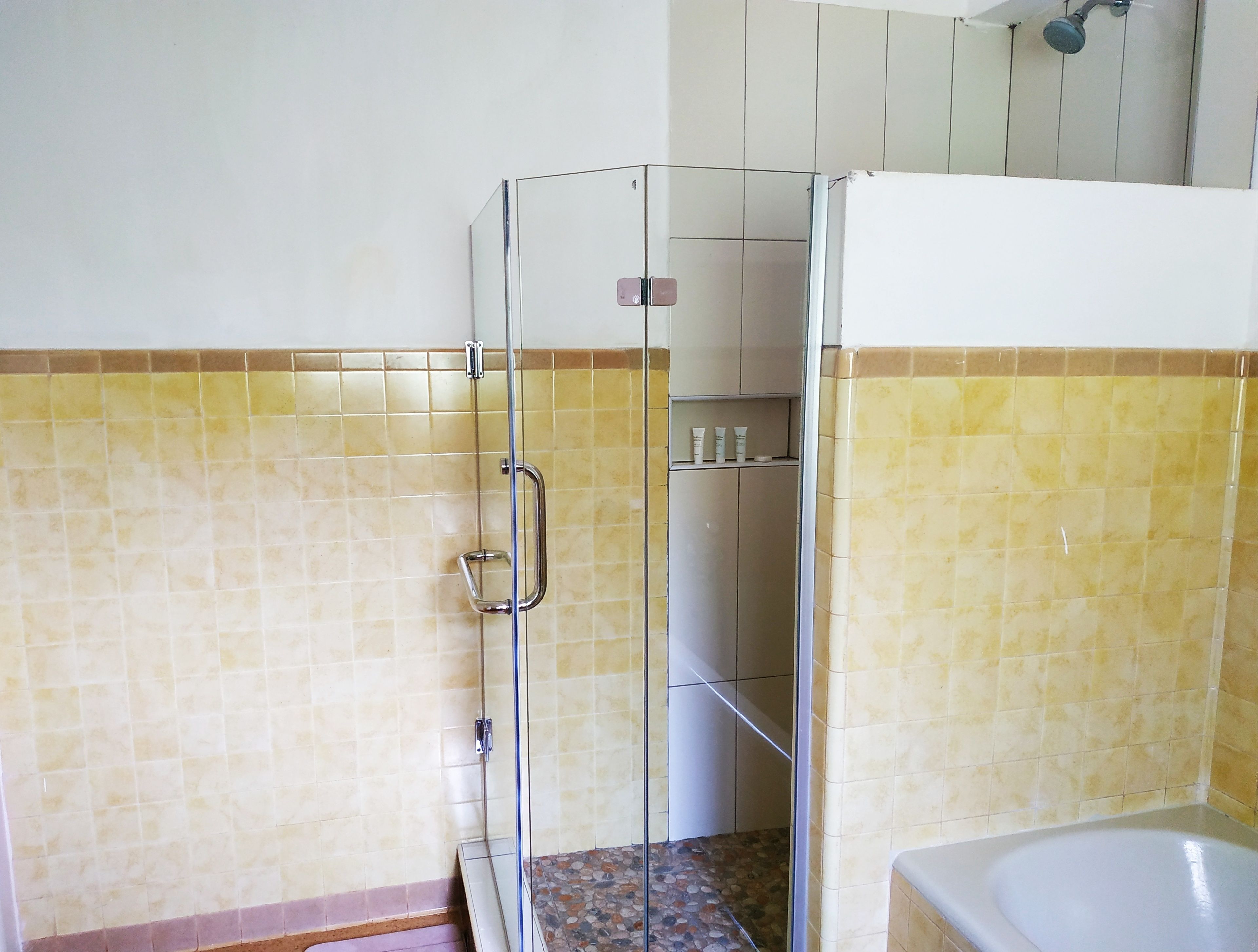 A bathroom with a shower enclosure, tiled walls, and a bathtub.