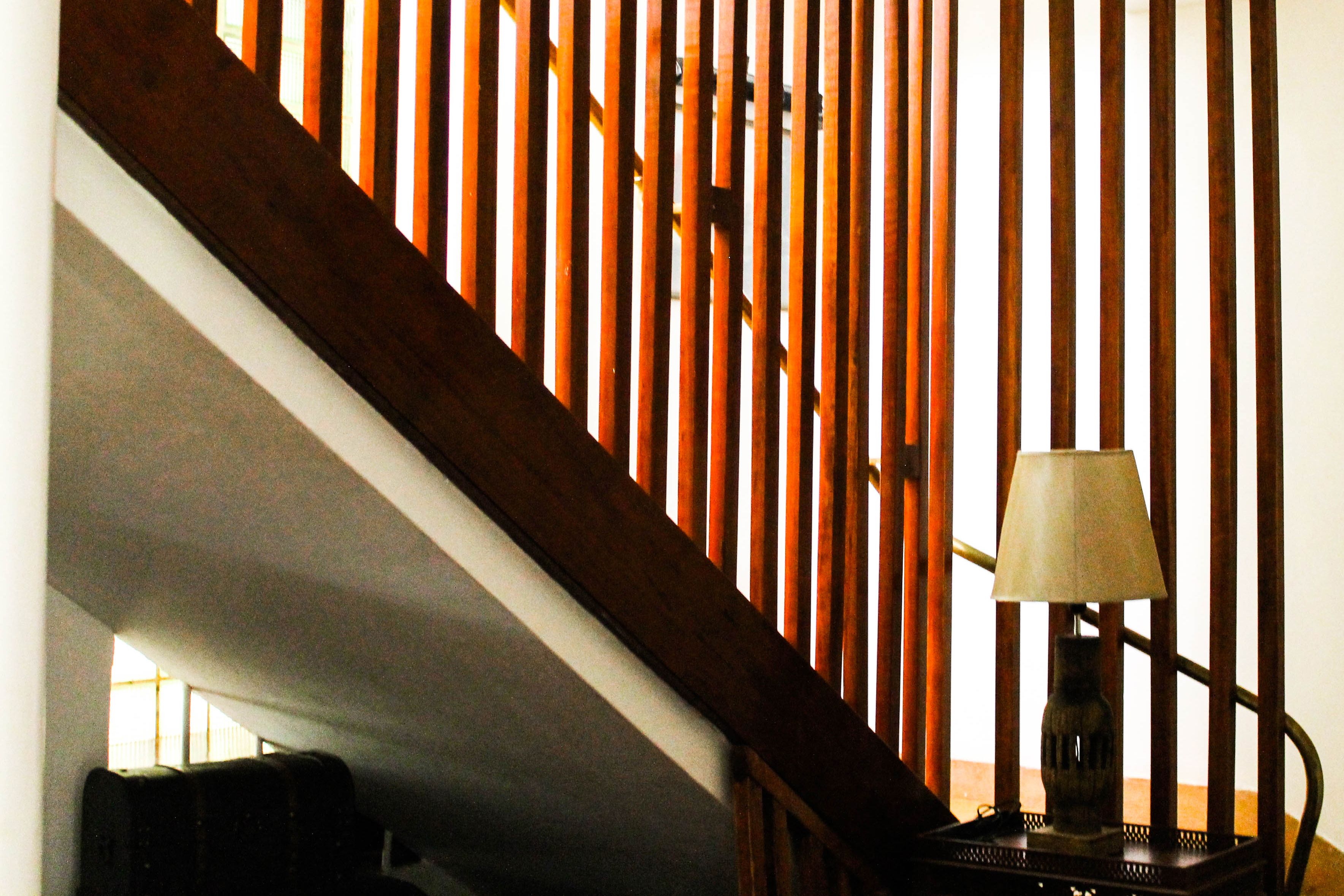Una escalera con barandillas de madera y una lámpara sobre una mesa.