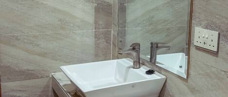 A bathroom with a white sink, a mirror, and a shower area.