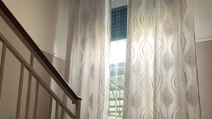A staircase with a wooden handrail and a view of a window with patterned curtains. - Hotel Belvedere (Savignano sul Panaro)