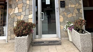 A hotel entrance with a stone facade, a glass door, and a balcony above. - Hotel Belvedere (Savignano sul Panaro)