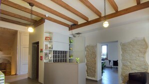 A spacious living area with a kitchen, stone wall, and a view of a garden through a window. - Hotel Belvedere (Savignano sul Panaro)