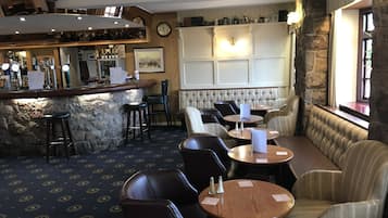 Eine Bar mit Sitzstühlen, einer Theke und einer Sitzecke mit Tischen und Stühlen.