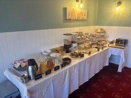Una mesa de buffet con diversos alimentos y bebidas, que incluye una estación de café y un tostador.