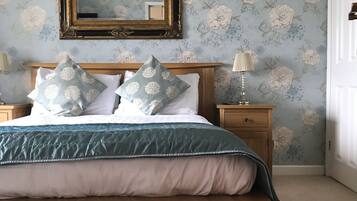 Un dormitorio con cama de madera, papel tapiz floral, un espejo y lámparas de noche.