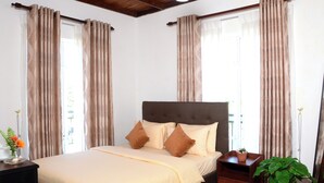A bedroom with a bed, nightstand, and potted plant. - The Fern Inn (Nuwara Eliya)
