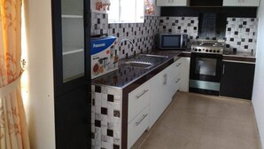 A kitchen with a microwave, stove, and a Panasonic rice cooker. - The Fern Inn (Nuwara Eliya)