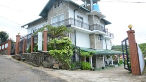 A two-story house with a balcony, a water tank on the roof, and a gated entrance. - The Fern Inn (Nuwara Eliya)