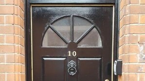 Une porte noire portant le numéro 10, un heurtoir en laiton et une fente pour le courrier.