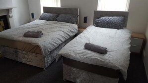 Une chambre double avec deux lits, chacun doté d’une tête de lit, de tables de chevet et de lampes.
