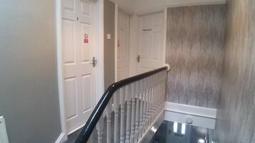 Una escalera con puertas blancas, algunas que indican 'PRIVATE', y una pared con un diseño de árbol.