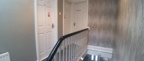 A staircase with white doors, some marked 'PRIVATE,' and a wall with a tree pattern.