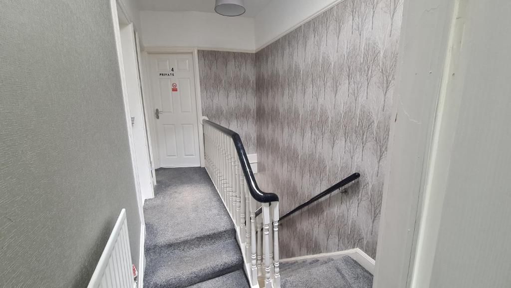 A staircase with a handrail, carpeted steps, and a door labeled 'PRIVATE' in the background.