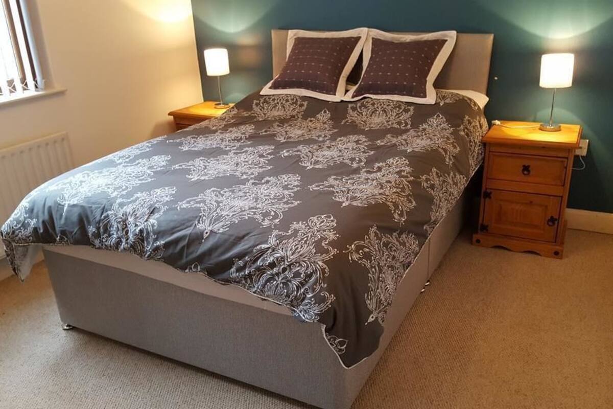 Ein Schlafzimmer mit einem Bett, zwei Nachttischen und einem Beistelltisch.