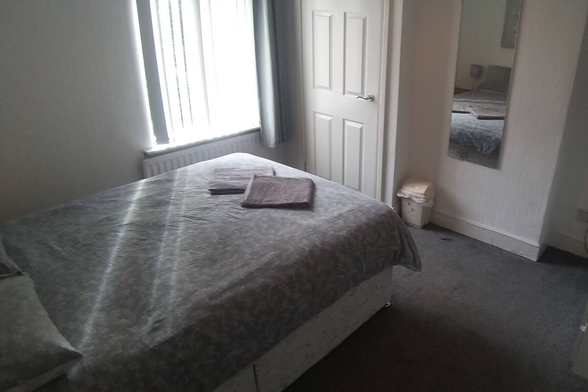 Ein Schlafzimmer mit Bett, Fernseher, Heizkörper und Tür.