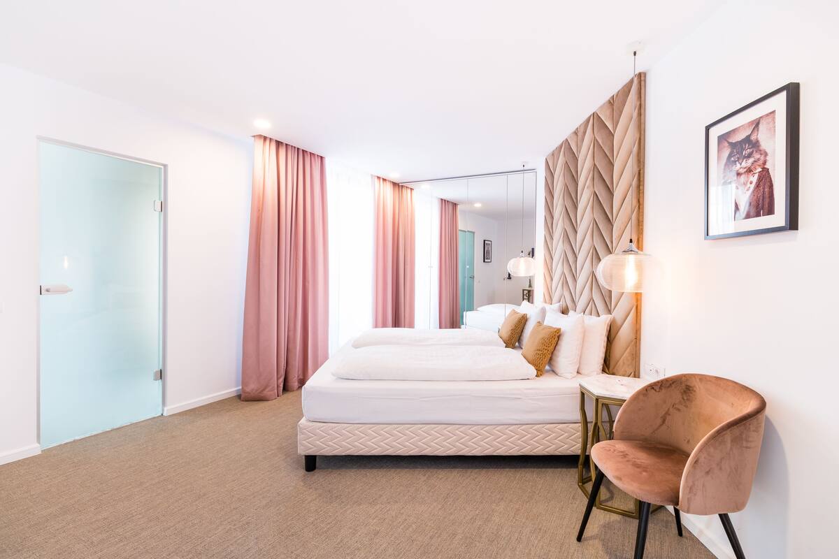 A modern hotel room with a large bed, a desk, and a chair.