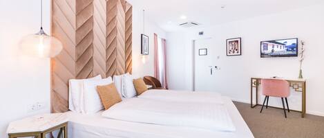 A modern hotel room with a large bed, a desk, and a television.
