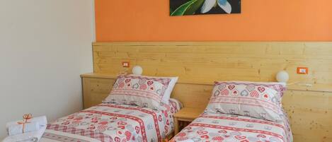 A double room with two beds, each with matching red and white patterned bedding.