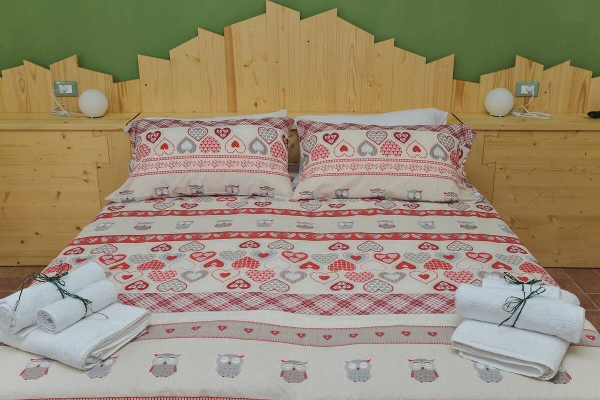 Una cama con ropa de cama estampada, dos mesitas de noche con lámparas y toallas en el suelo.