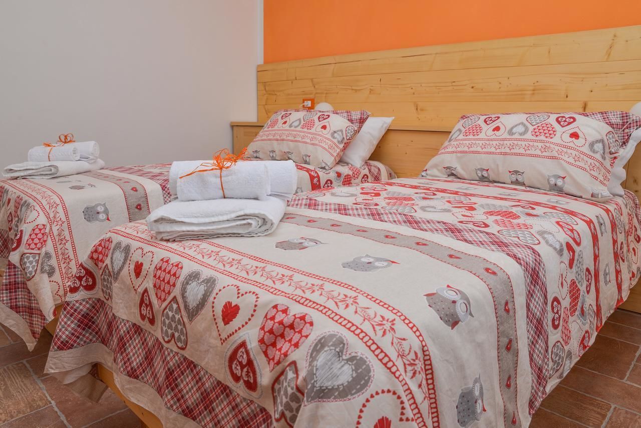 A hotel room with two beds, each with a red and white patterned bedspread and matching pillows. There are towels neatly folded on each bed.