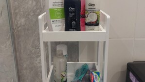 A bathroom shelf with various toiletries including a shower gel, conditioner, and a toothbrush. - Lawnbrook Town Guest House (Belfast)
