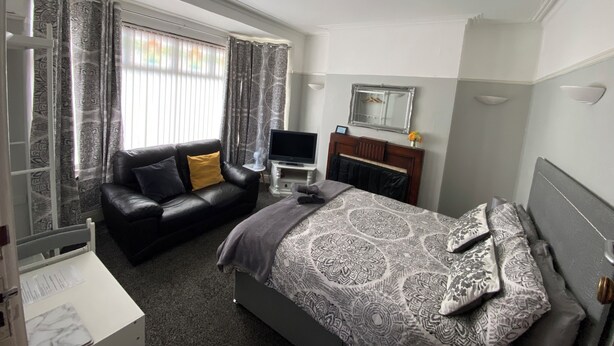 A hotel room with a bed, a sofa, a TV, and a mirror. - Crumlin Road Guesthouse (Belfast)