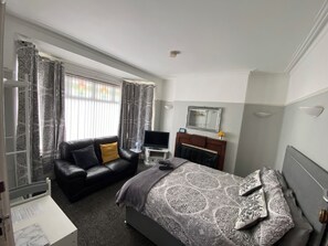 Una habitación de hotel con cama, sofá, televisión y espejo.