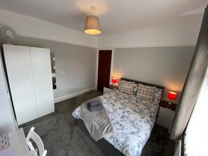 A bedroom with a bed, bedside tables, a wardrobe, and a ceiling fan. - Crumlin Road Guesthouse (Belfast)